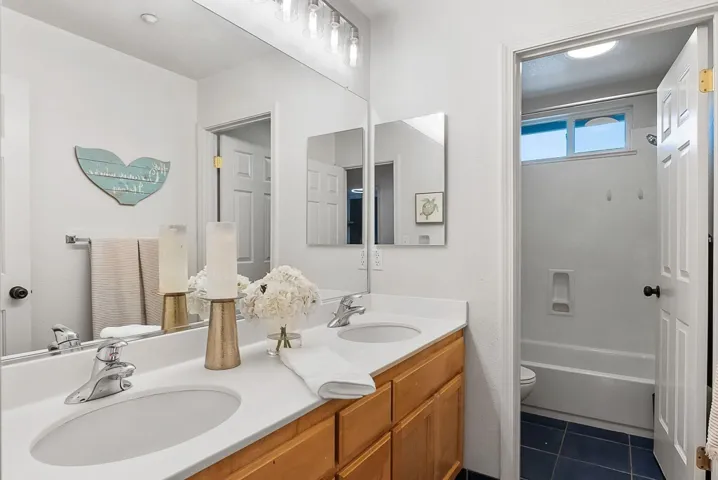 Full bathroom featuring double vanity, bathing tub / shower combination, and dark tile patterned floors