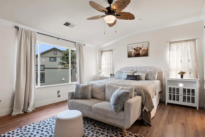 Bedroom featuring crown molding, vaulted ceiling, wood finished floors, and ceiling fan