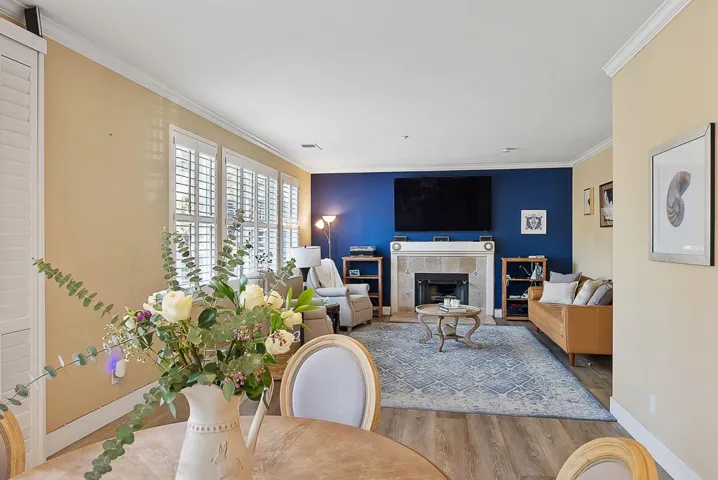 Living area with wood finished floors, crown molding, and a premium fireplace