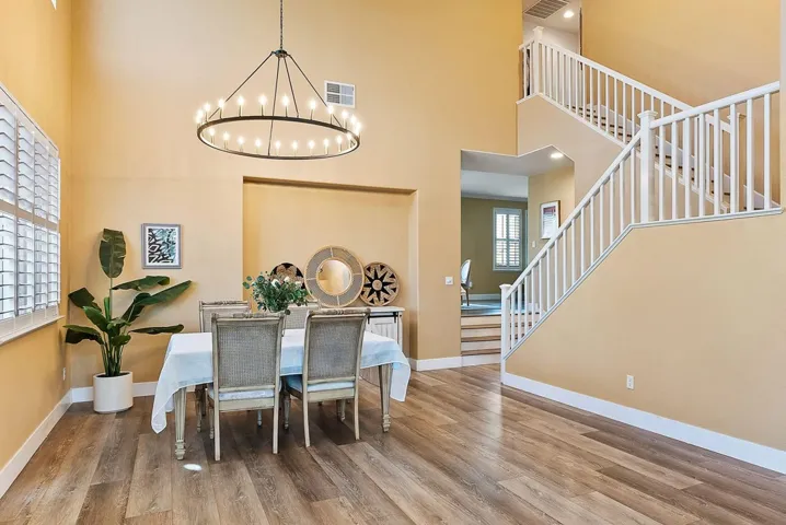 Dining room with stairway, wood finished floors, and a high ceiling