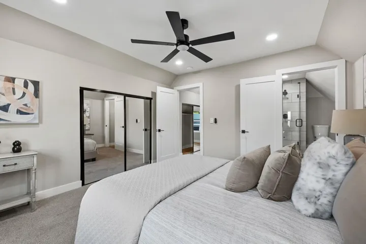 Bedroom featuring ensuite bathroom, vaulted ceiling, light colored carpet, a ceiling fan, and recessed lighting