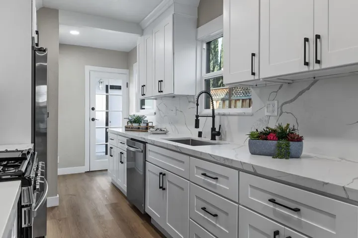 Kitchen featuring light stone countertops, dark wood finished floors, white cabinets, appliances with stainless steel finishes, and tasteful backsplash