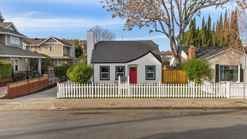 View of front of home featuring a chimney, a fenced front yard, roof with shingles, and a residential view