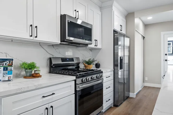 Kitchen featuring stainless steel appliances, white cabinetry, tasteful backsplash, and dark wood-type flooring