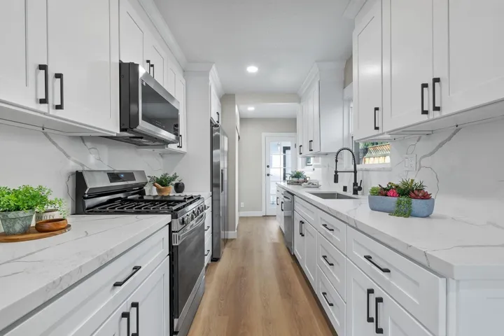 Kitchen featuring appliances with stainless steel finishes, light stone counters, light wood-type flooring, white cabinets, and recessed lighting