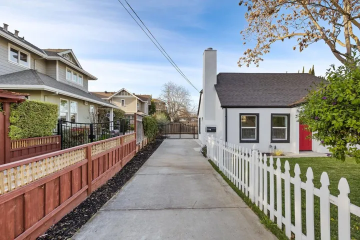 View of side of home featuring a chimney, roof with shingles, a gate, and a residential view