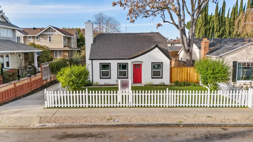 View of front of property with a fenced front yard, a shingled roof, a residential view, stucco siding, and a chimney