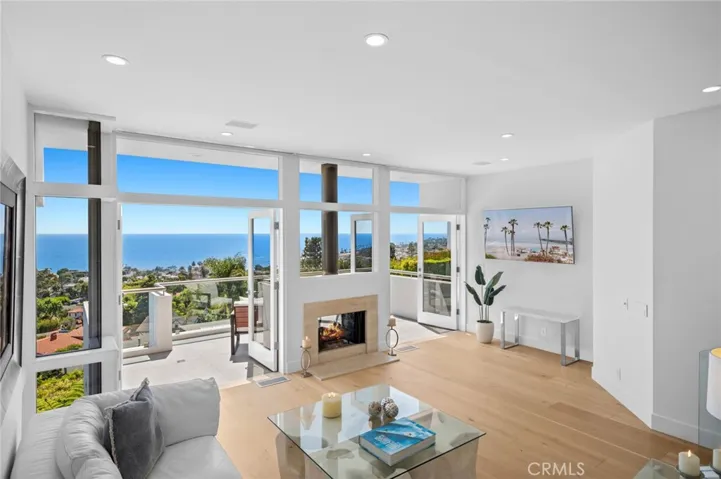 Thoughtfully upgraded with timeless elegance, the home features a soft, neutral palette that compliments wide-plank hardwood flooring, vaulted ceilings, and expansive walls of glass that flood the interiors with natural light and perfectly frame the dramatic ocean views.