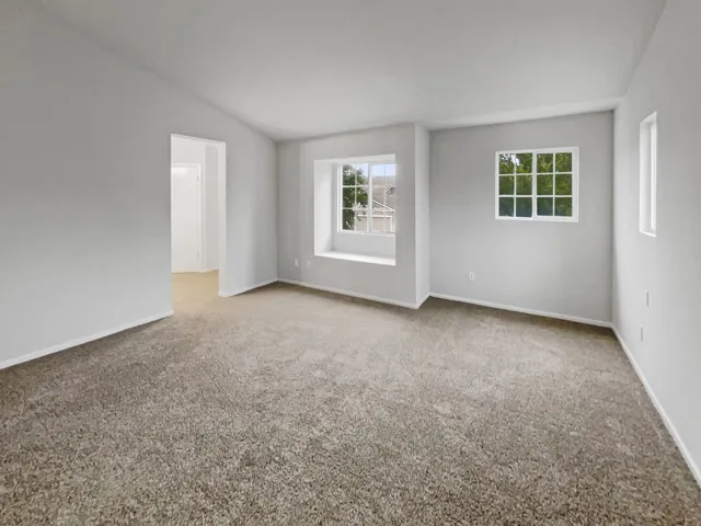 Unfurnished room featuring light colored carpet and lofted ceiling