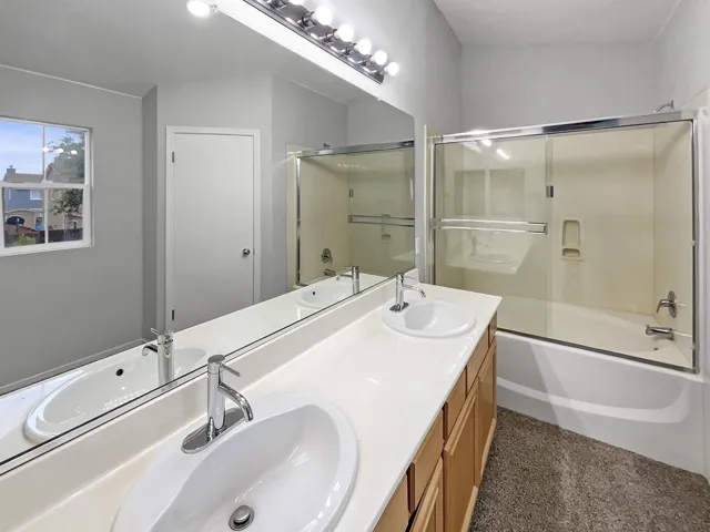 Bathroom with double vanity and enclosed tub / shower combo