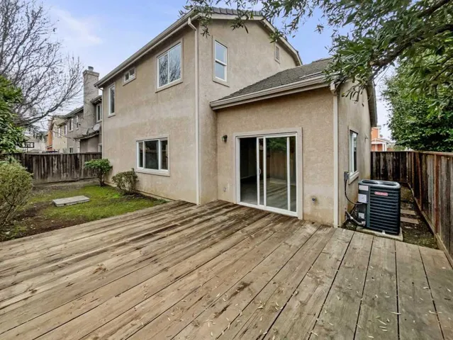 Back of property with a fenced backyard, stucco siding, and a wooden deck
