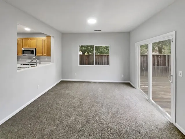 Unfurnished living room with dark colored carpet, plenty of natural light, and recessed lighting