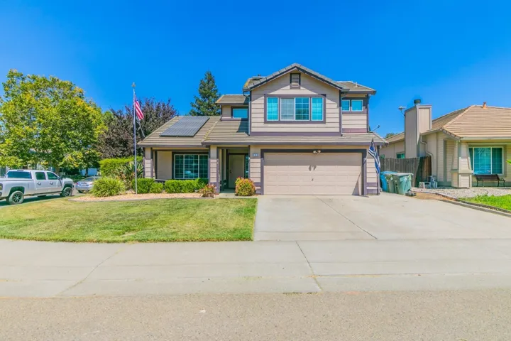Traditional-style house featuring a garage, roof mounted solar panels, and driveway