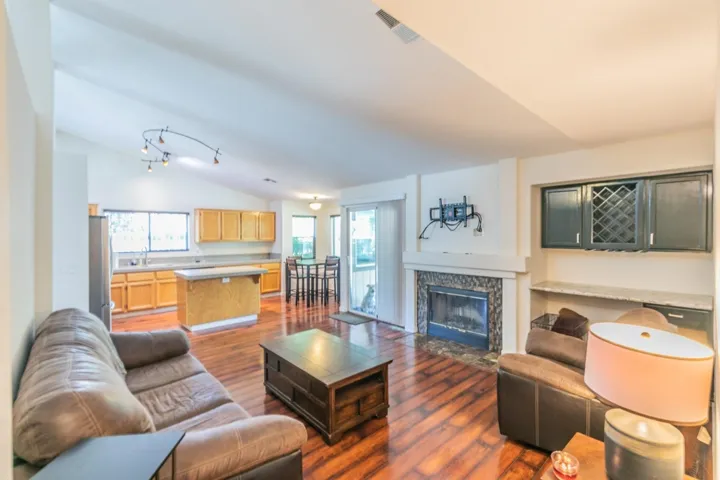 Living room featuring a fireplace with flush hearth, dark wood-style floors, and vaulted ceiling