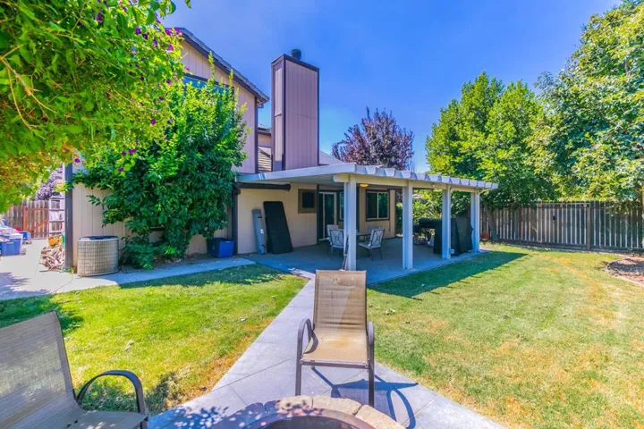Back of house with a fenced backyard, a patio, and a chimney