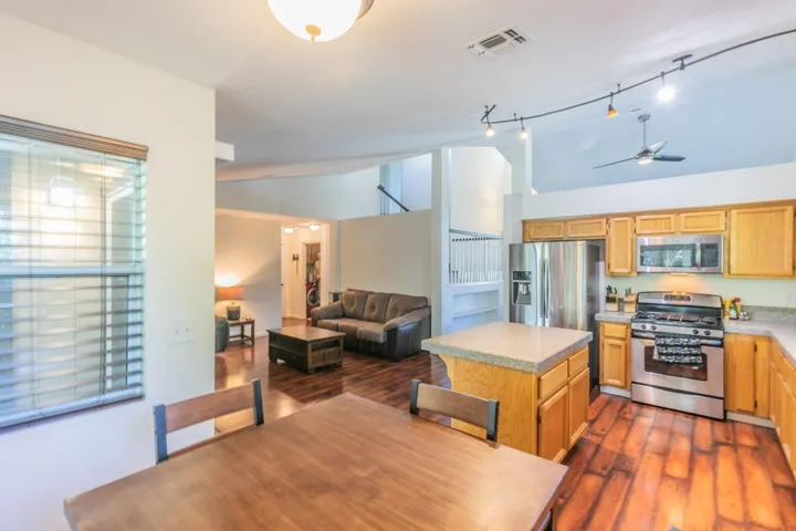 Kitchen featuring appliances with stainless steel finishes, light countertops, open floor plan, a ceiling fan, and a kitchen island