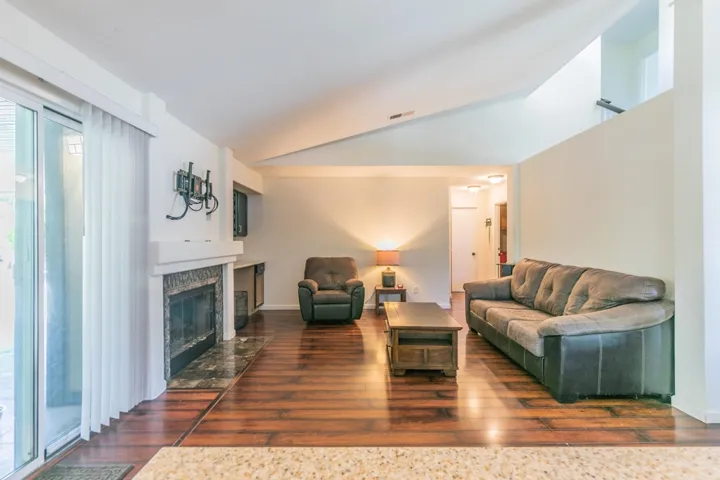 Living area with dark wood-style floors, lofted ceiling, and a fireplace