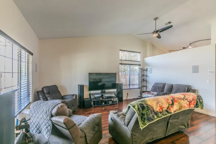 Living area with a ceiling fan, wood finished floors, and high vaulted ceiling