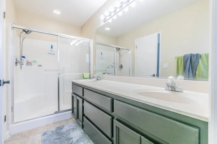 Full bath featuring double vanity, a shower stall, and recessed lighting