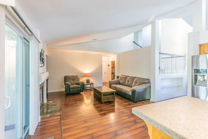 Living area featuring lofted ceiling, a fireplace, and dark wood-style flooring