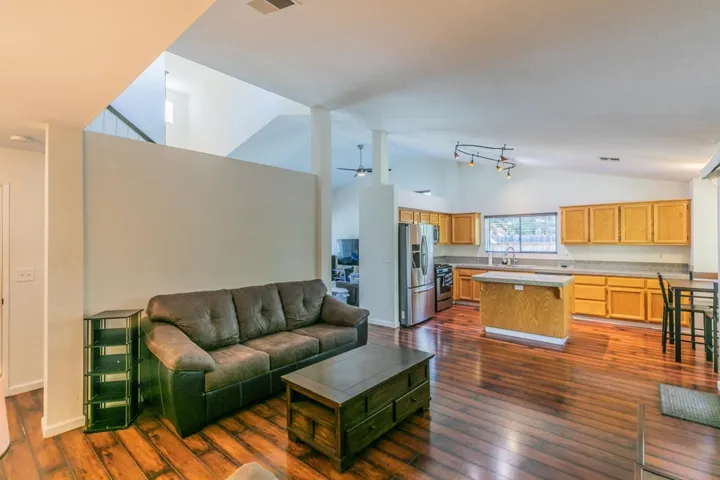 Living area featuring high vaulted ceiling, dark wood-type flooring, and a ceiling fan