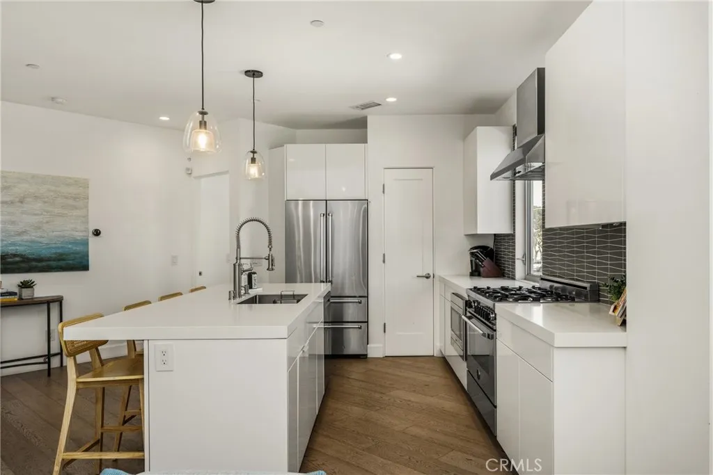 The chef’s kitchen is appointed with quartz countertops, a generous center island, modern European-style cabinetry, and premium stainless-steel appliances.
