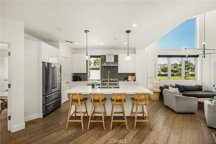 The chef’s kitchen is appointed with quartz countertops, a generous center island, modern European-style cabinetry, and premium stainless-steel appliances.