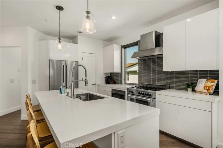 The chef’s kitchen is appointed with quartz countertops, a generous center island, modern European-style cabinetry, and premium stainless-steel appliances.