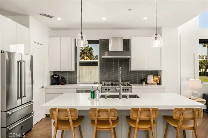 The chef’s kitchen is appointed with quartz countertops, a generous center island, modern European-style cabinetry, and premium stainless-steel appliances.
