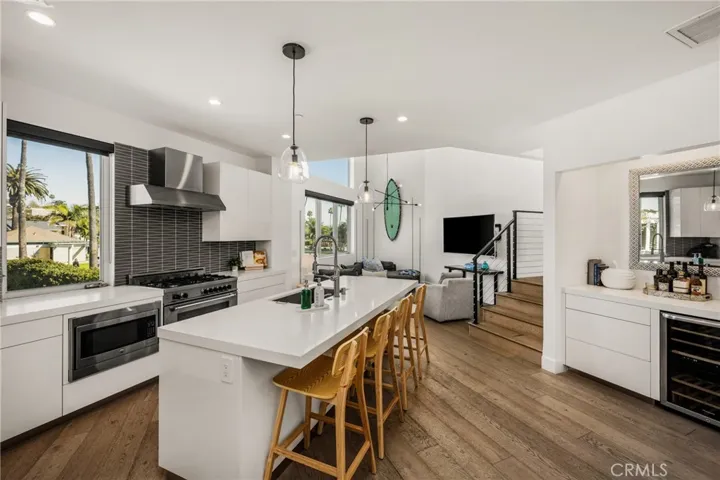 The chef’s kitchen is appointed with quartz countertops, a generous center island, modern European-style cabinetry, and premium stainless-steel appliances and opens to living area.
