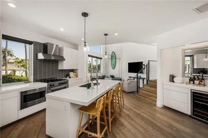 The chef’s kitchen is appointed with quartz countertops, a generous center island, modern European-style cabinetry, and premium stainless-steel appliances and opens to living area.