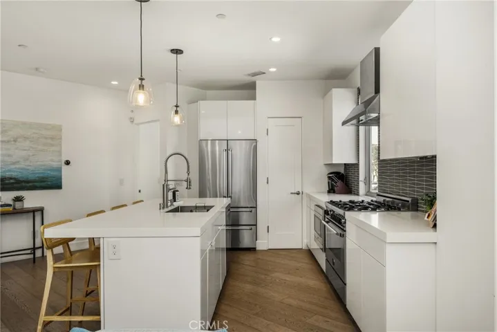 The chef’s kitchen is appointed with quartz countertops, a generous center island, modern European-style cabinetry, and premium stainless-steel appliances.