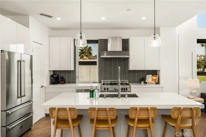 The chef’s kitchen is appointed with quartz countertops, a generous center island, modern European-style cabinetry, and premium stainless-steel appliances.