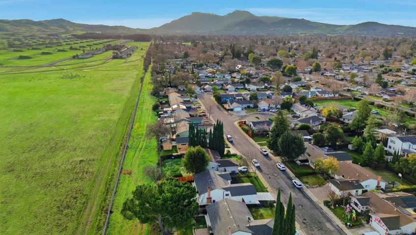 Aerial overview of property's location featuring a mountain backdrop and nearby suburban area