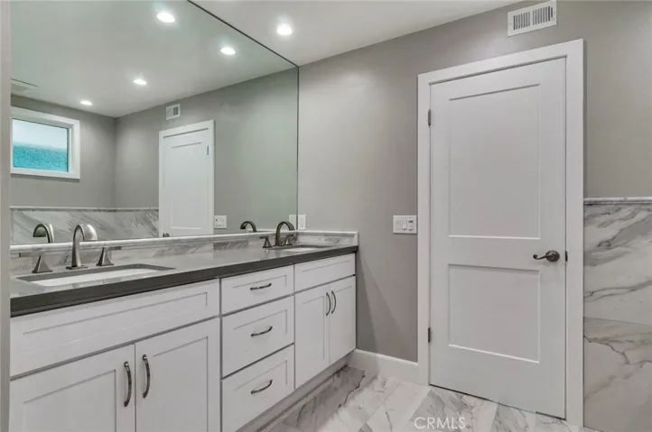 Primary bathroom with dual sinks and marble flooring