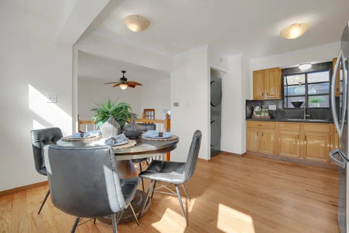 Dining area with light wood-style flooring, crown molding, ceiling fan, and stacked washer and clothes dryer