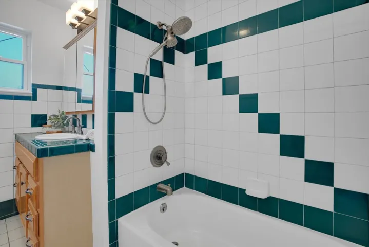 Full bath featuring tile walls, shower / bath combination, and vanity