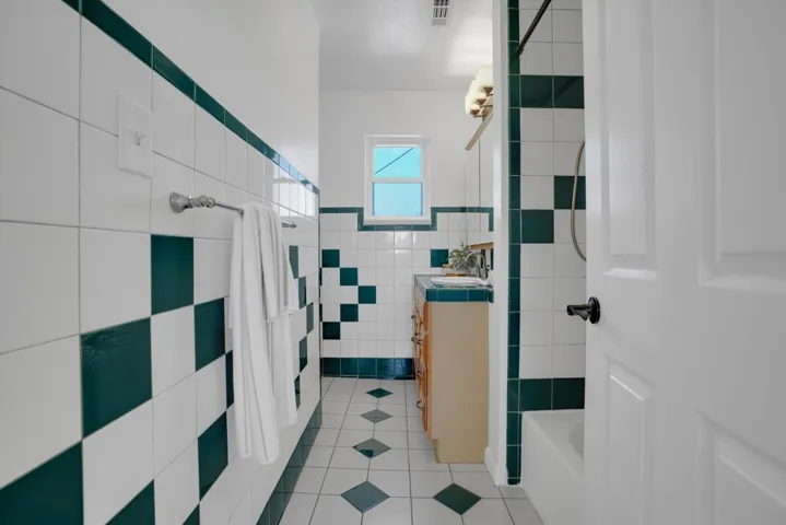 Bathroom with vanity, light tile patterned floors, tile walls, and shower / bathtub combination with curtain