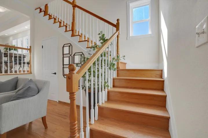 Stairs featuring wood finished floors and plenty of natural light