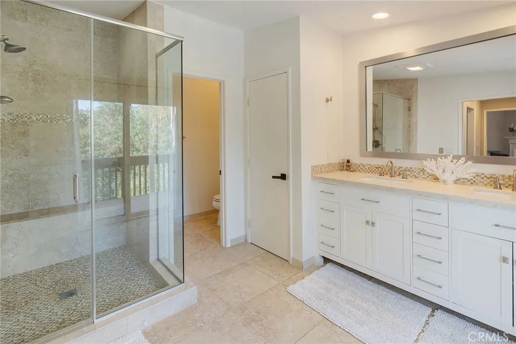 Remodeled Primary Bath with double vanities, Huge Walk In Shower and Bench, Private toilet and more storage in closet.