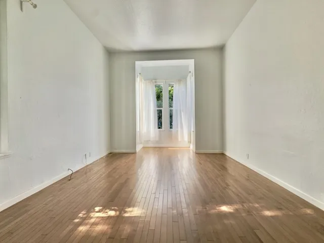Empty room with hardwood / wood-style floors and french doors
