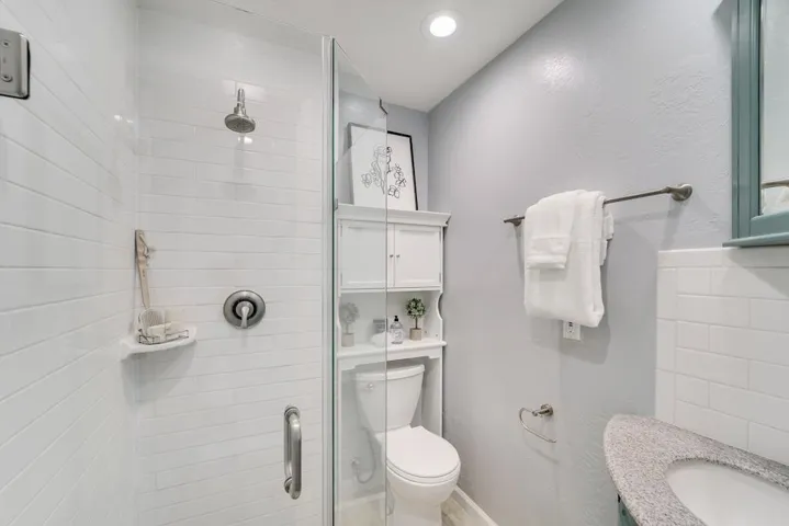 Full bathroom with a shower stall, vanity, a textured wall, and recessed lighting