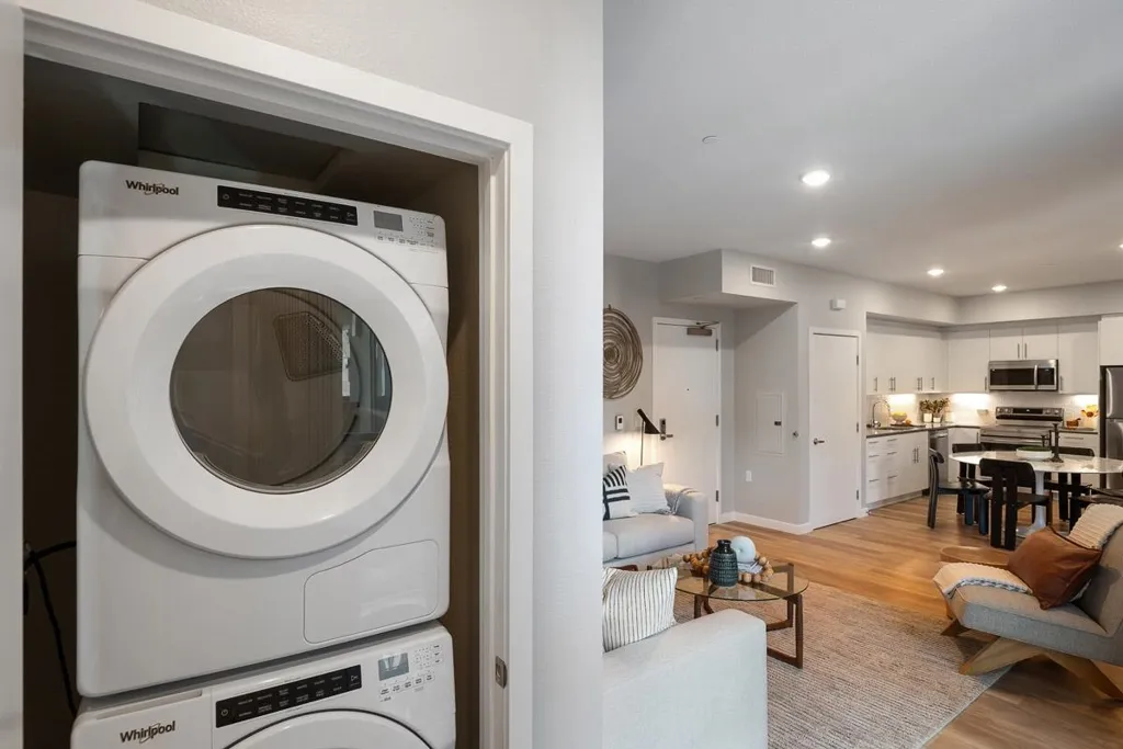 Laundry area with light wood-style flooring, estacked washer and dryer, and recessed lighting