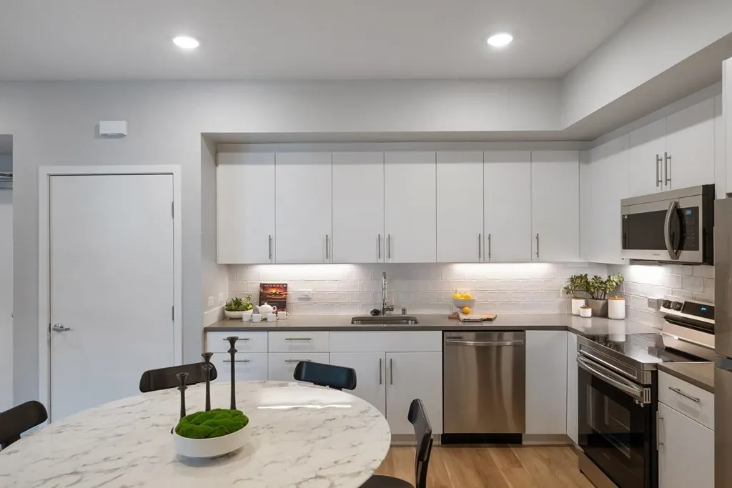 Kitchen with appliances with stainless steel finishes, white cabinets, light wood-type flooring, backsplash, and recessed lighting