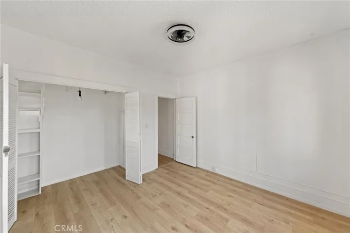 The bedroom includes a built-in closet with white louvered doors and shelving