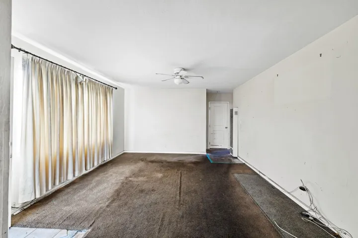 Spare room with a ceiling fan and dark carpet