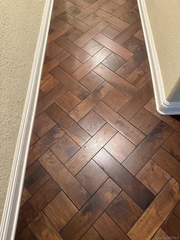 Herring bone hardwood floor pattern in solid walnut in hallway, entry, and dining room.