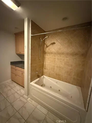 hallway bath has jacuzzi style tub with additional built in cabinets for storage and linens