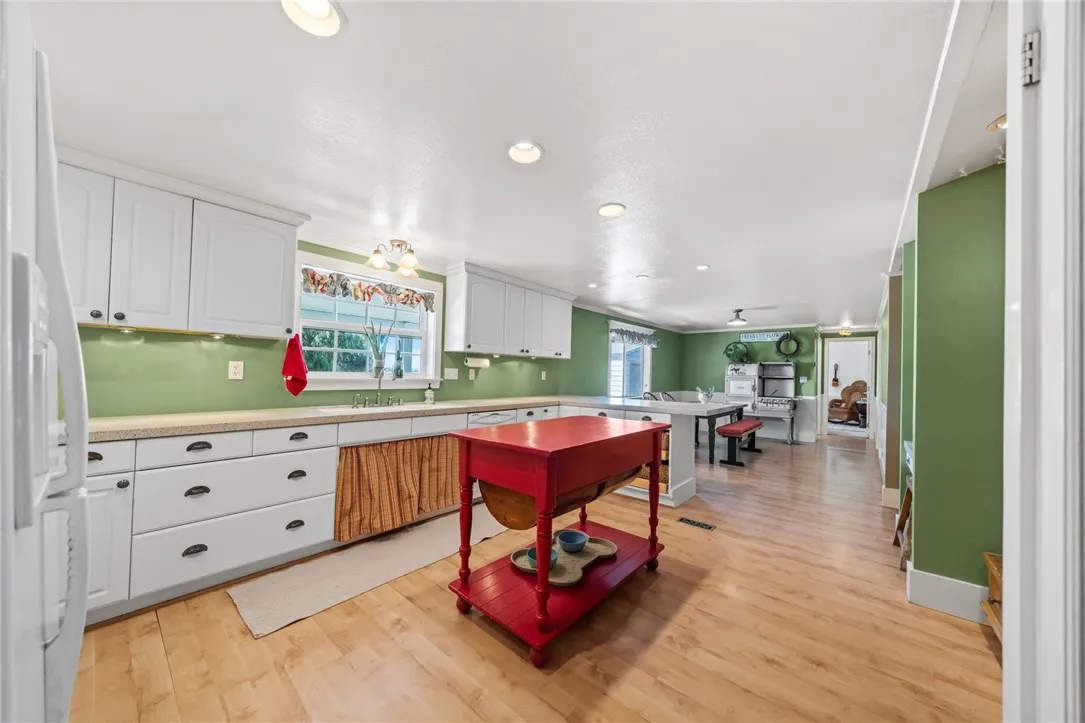 Kitchen wiht quartz counters, double sink, dishwasher, stove and glassed door pantry