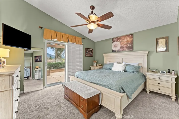 Primary Bedroom has Vaulted Ceiling and Slider with View of Golf Course and Mountains